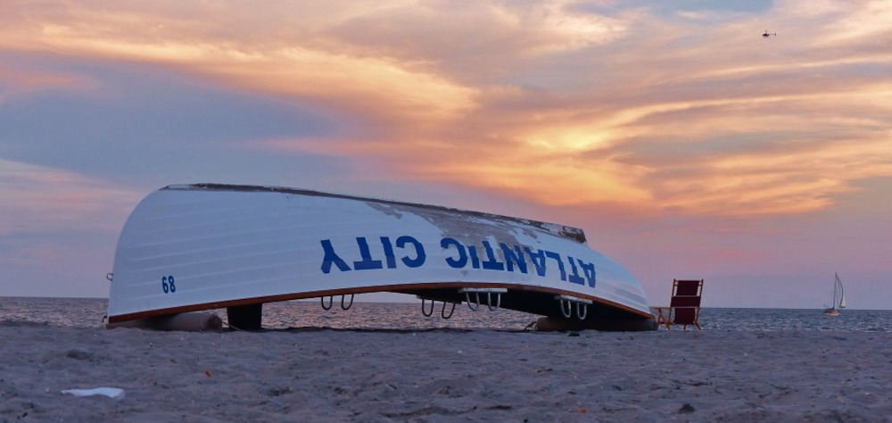 Photo of rowboat on beach, boat has "ATLANTIC CITY" written on the side, in reference to the gambling capital of New Jersey, where most of the state's retail gambling revenue comes from.